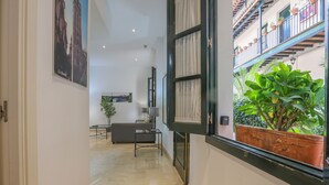Ein Flur mit Blick auf einen Balkon mit Topfpflanzen, einem Sofa und einer Lampe.