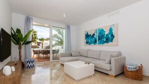 A modern living room with a grey sectional sofa, a white coffee table, a flat-screen TV, and a large abstract painting. - Saladillo in Estepona (Estepona)