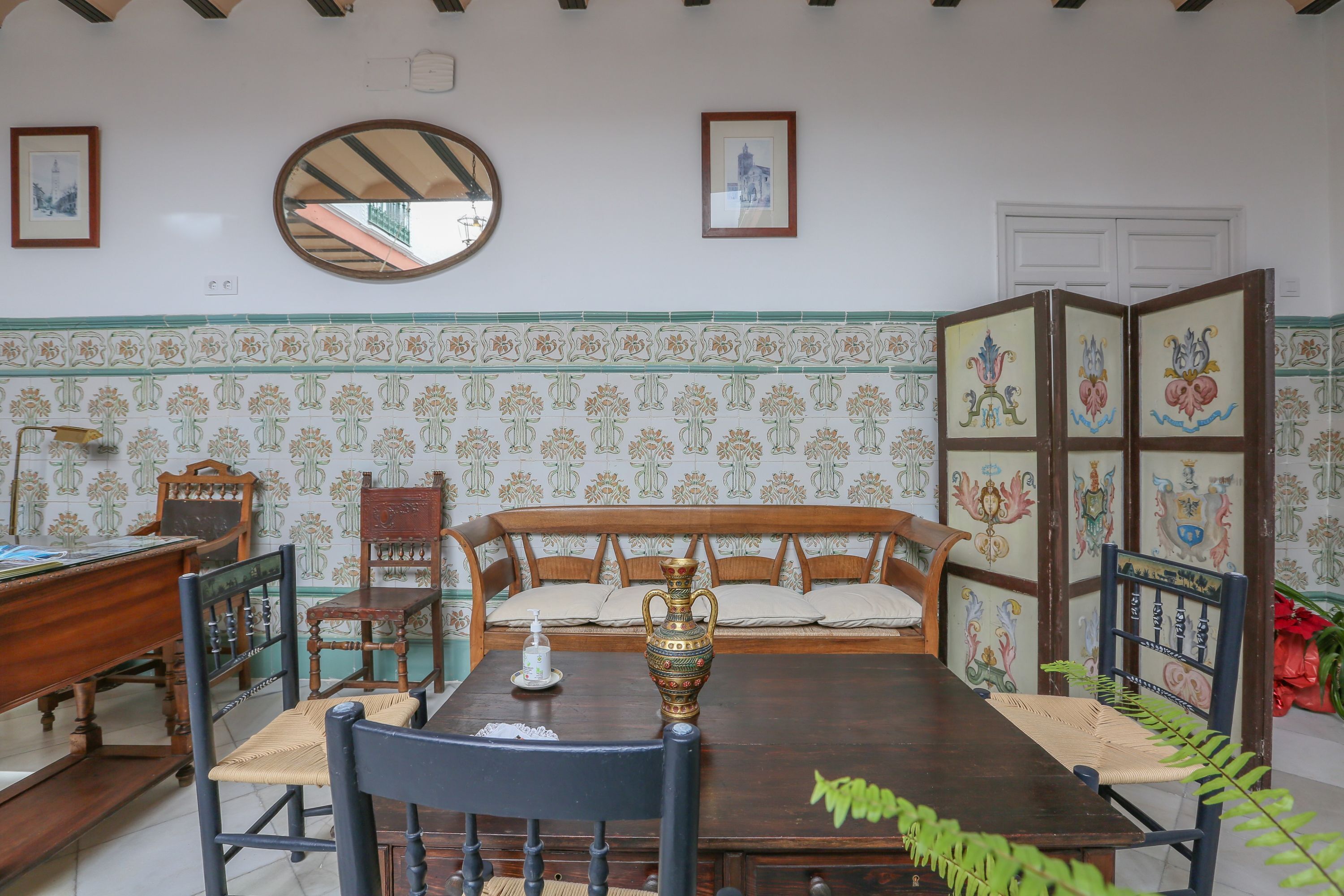 Un comedor con mesa de madera, sillas, un banco y un florero decorativo.