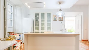 A kitchen with a central island, white cabinets, a sink, and a pendant light. - Posada De La Casa Del Pintor Hab Granada - Adults Only (Carmona)