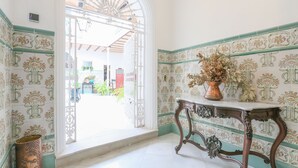 A hallway with ornate tiled walls, a decorative table with a vase, and an open doorway leading outside. - Posada De La Casa Del Pintor Hab Almeria - Adults Only (Carmona)