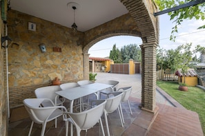 Une terrasse extérieure avec des murs en pierre, une table et des chaises.