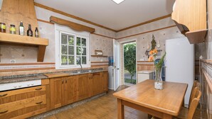 Eine Küche mit Holzausstattung, einer Granitarbeitsplatte, einem weißen Kühlschrank und einem Esstisch mit Stühlen.
