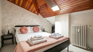 A bedroom with a bed, bedside tables, a radiator, and a ceiling with wooden beams. - Rovani 14 in Monza With 1 Bedrooms and 1 Bathrooms (Monza)