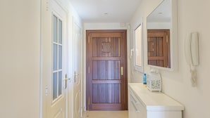 A hallway with a wooden door, a white counter with a phone, and a mirror. - Villa Riviera in Urbanizaci n Riviera Sol (Mijas)