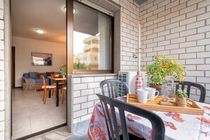 A balcony with a table, chairs, and potted plants.