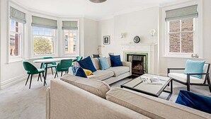 A living room with a sofa, chairs, a fireplace, and a dining area. - Serene 2BR - 3 Mins to Fulham Broadway (London)