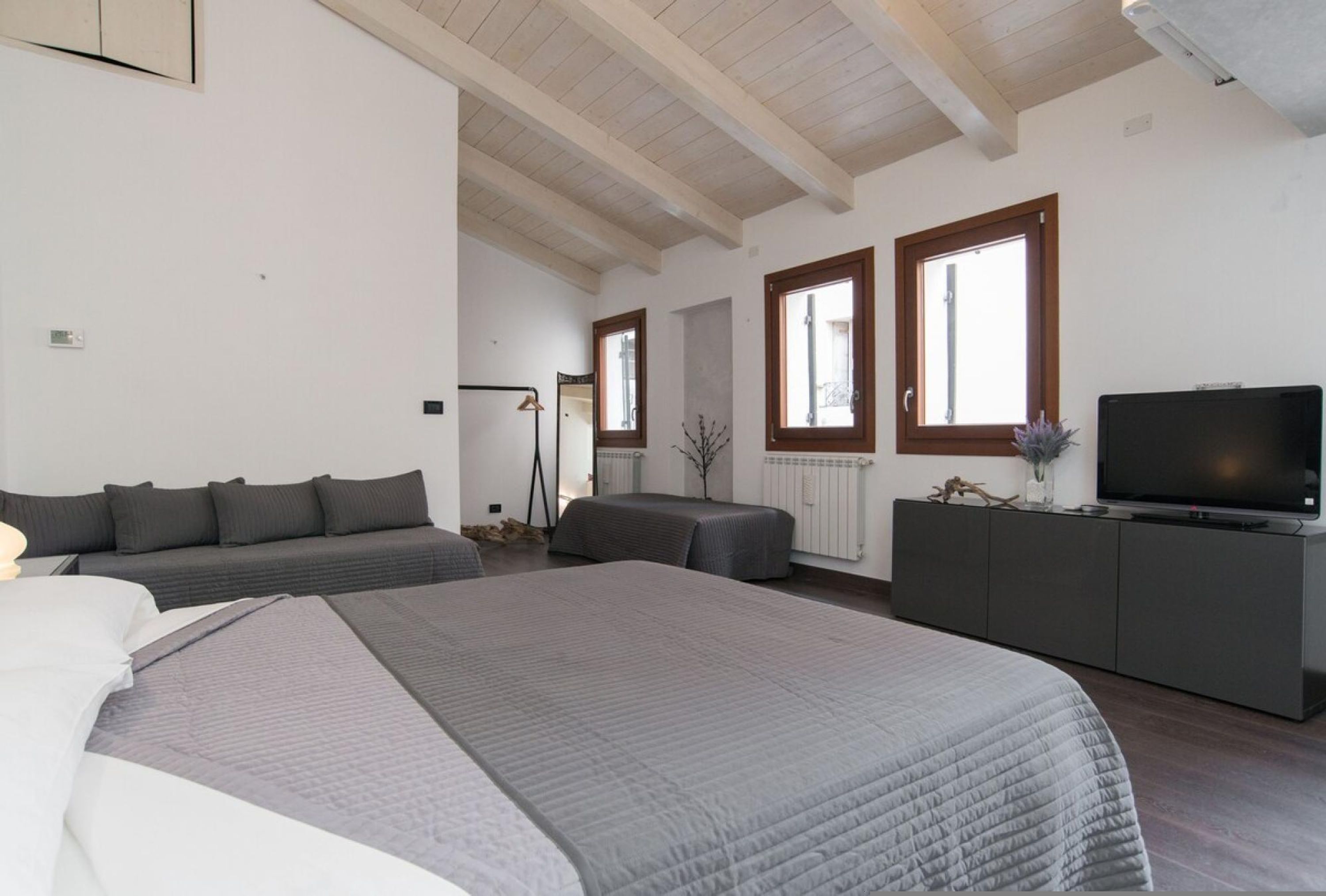 Una camera da letto con un letto grande, un divano, una TV e una finestra.