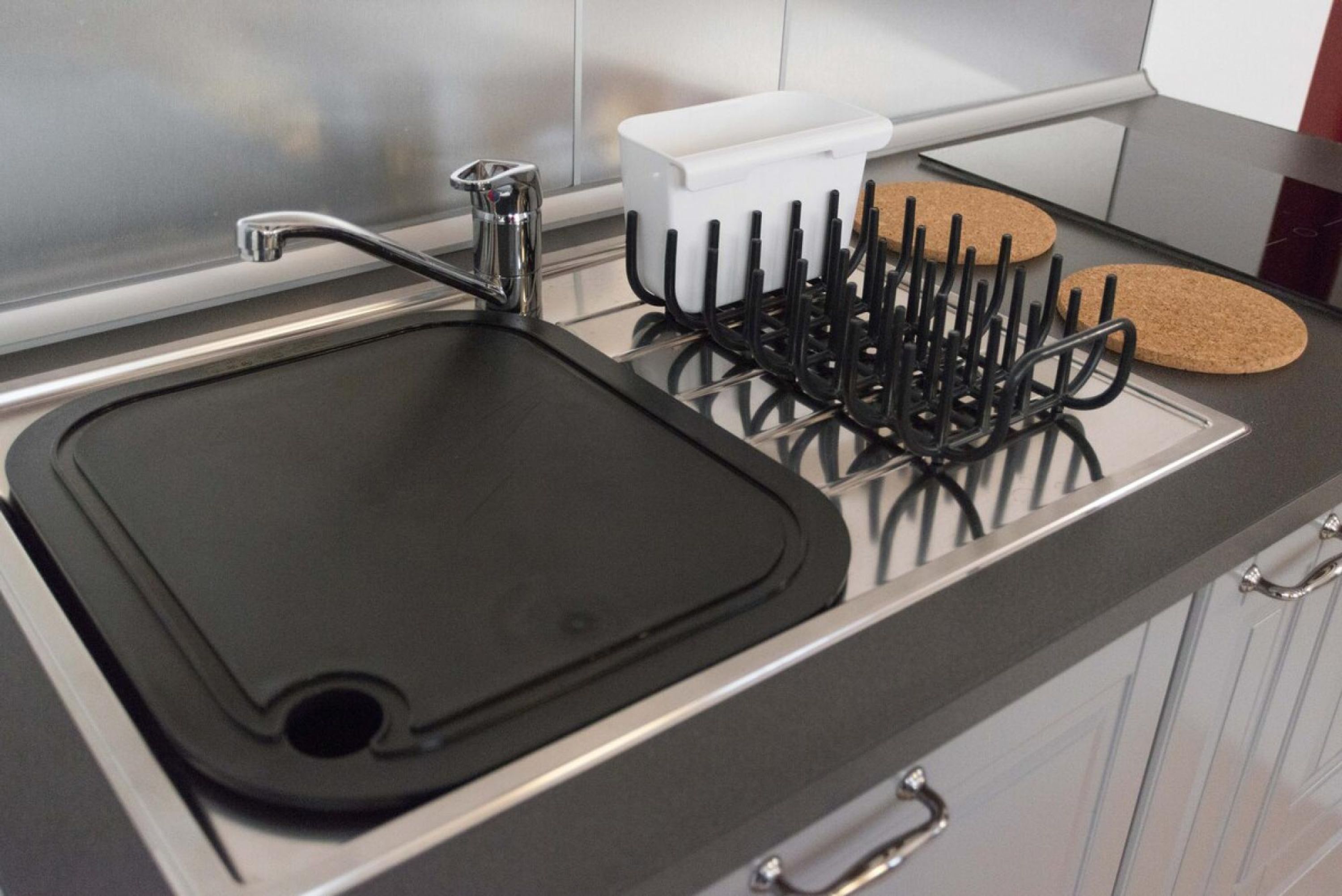 A kitchen with a black sink, a white container, and a utensil holder.