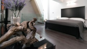 Ein modernes Schlafzimmer mit einem großen Bett, einer Holzskulptur auf einem Tisch und einer Blumenvase.