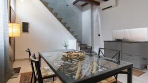 Eine moderne Küche mit einem Glastisch, einer Treppe und einer kleinen Kücheninsel.