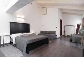 A modern bedroom with a large bed, a smaller bed, and a seating area with a chair and a table. - Luxury S A San Marco Palace 3mins From San Marco (Venice)