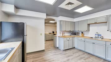 A modern kitchen with light grey cabinets, a black refrigerator, and a wooden countertop.