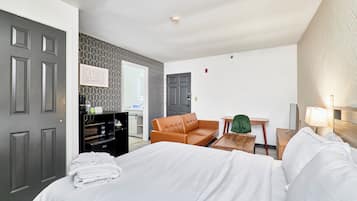 A hotel room with a bed, a sofa, a desk, and a mirror.