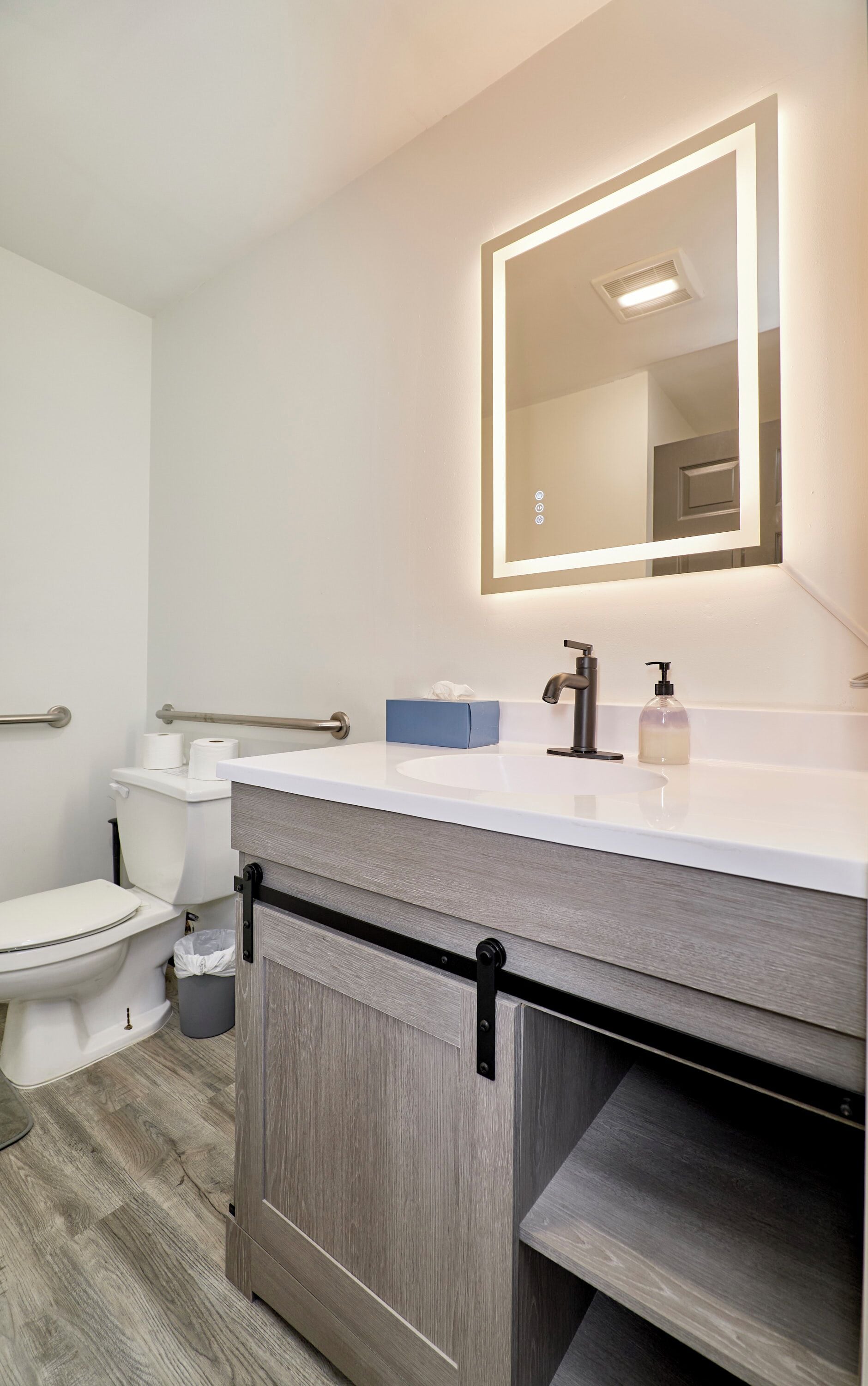A modern bathroom with a white sink, a mirror, and a toilet.