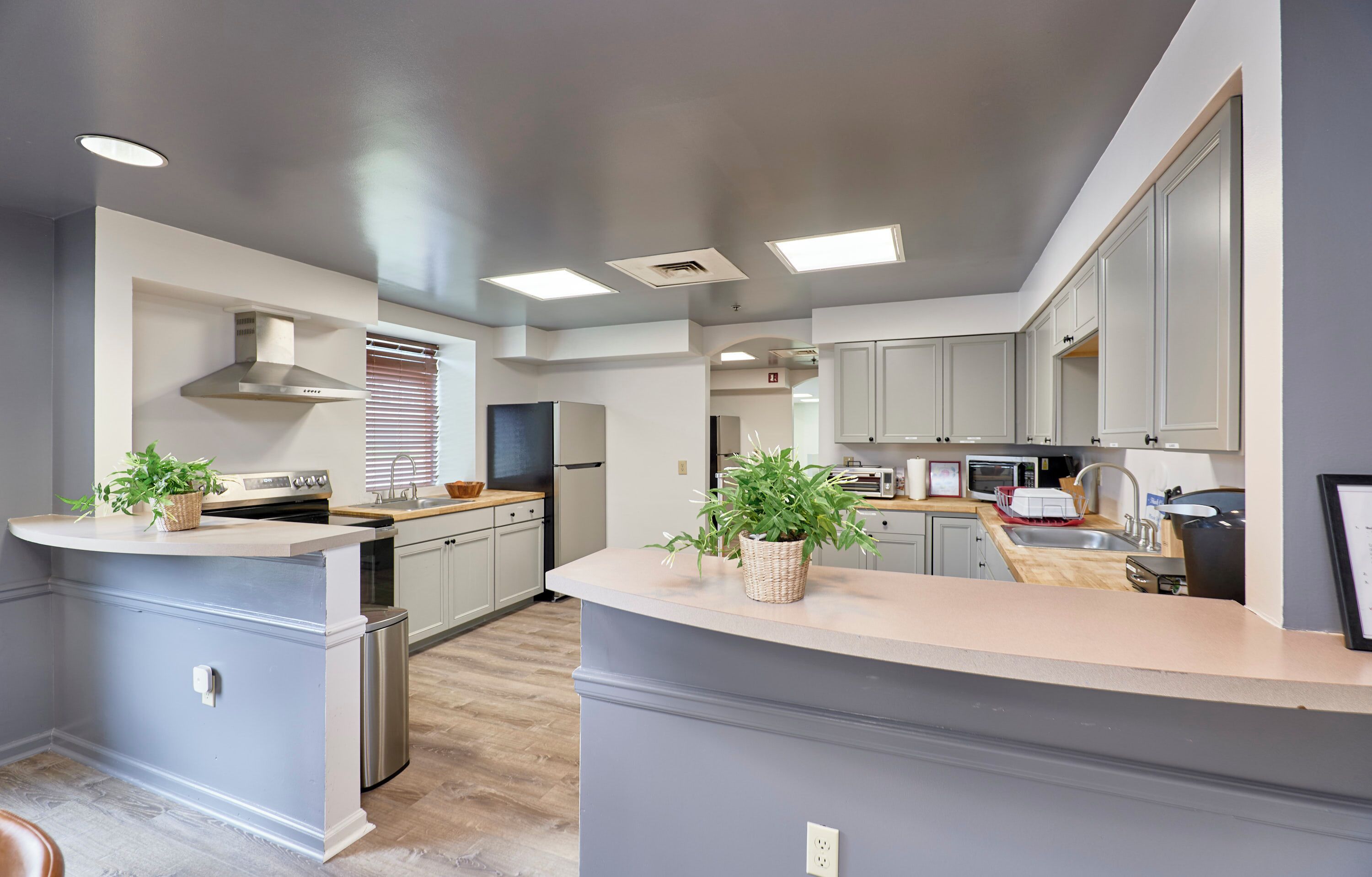 A modern kitchen with grey cabinets, a central island, and built-in appliances.