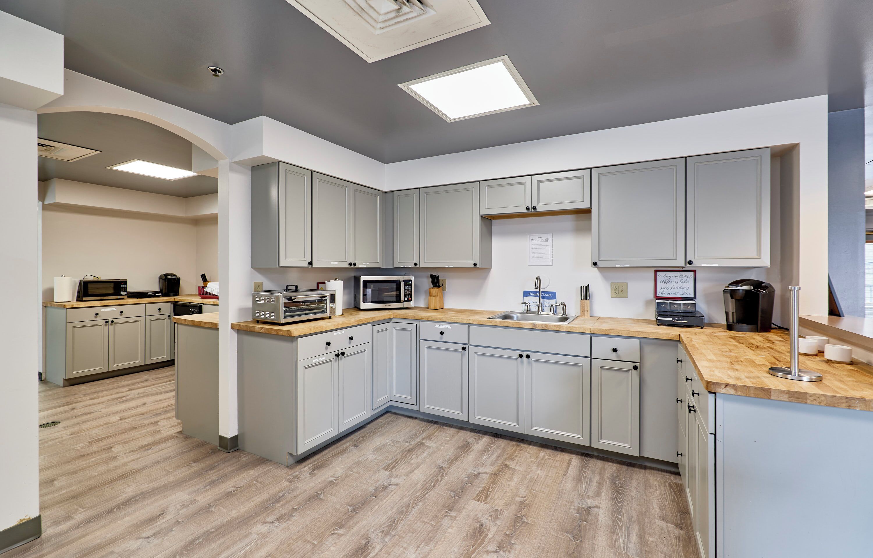A modern kitchen with grey cabinets, a wooden countertop, and built-in appliances.