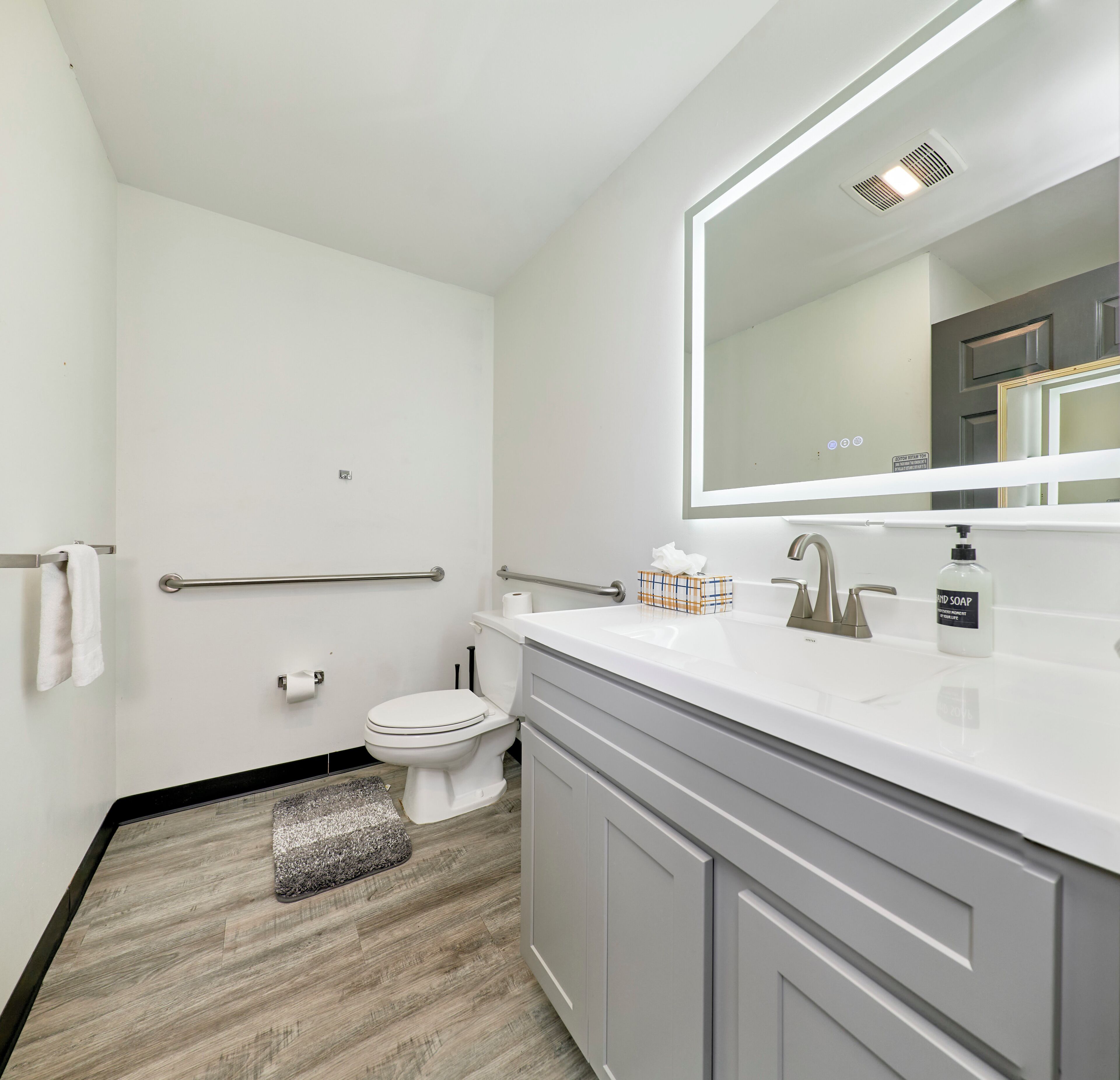 Een moderne badkamer met een wit wastafelmeubel, een spiegel en een toilet.