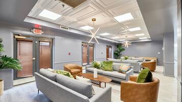 A modern lobby with grey sofas, a wooden coffee table, and a unique ceiling design.