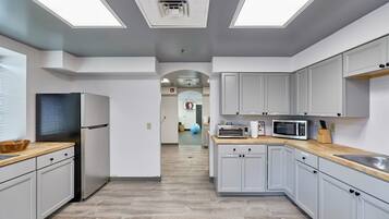 Une cuisine moderne avec des meubles gris, un réfrigérateur en acier inoxydable, un four à micro-ondes et un plan de travail en bois.