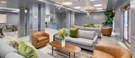 Un salon spacieux et moderne, avec un canapé gris, des fauteuils en cuir et une table basse.