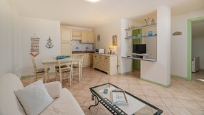 Un espacio habitable compacto con comedor, kitchenette y televisor.