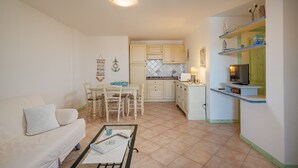 Un espacio habitable compacto con kitchenette, comedor y zona de estar.