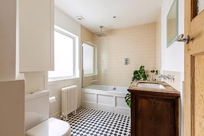 Une salle de bain comprenant des toilettes, une baignoire, un lavabo et une fenêtre.