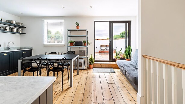 Una cucina moderna con mobili scuri, un tavolo da pranzo e vista su un balcone.