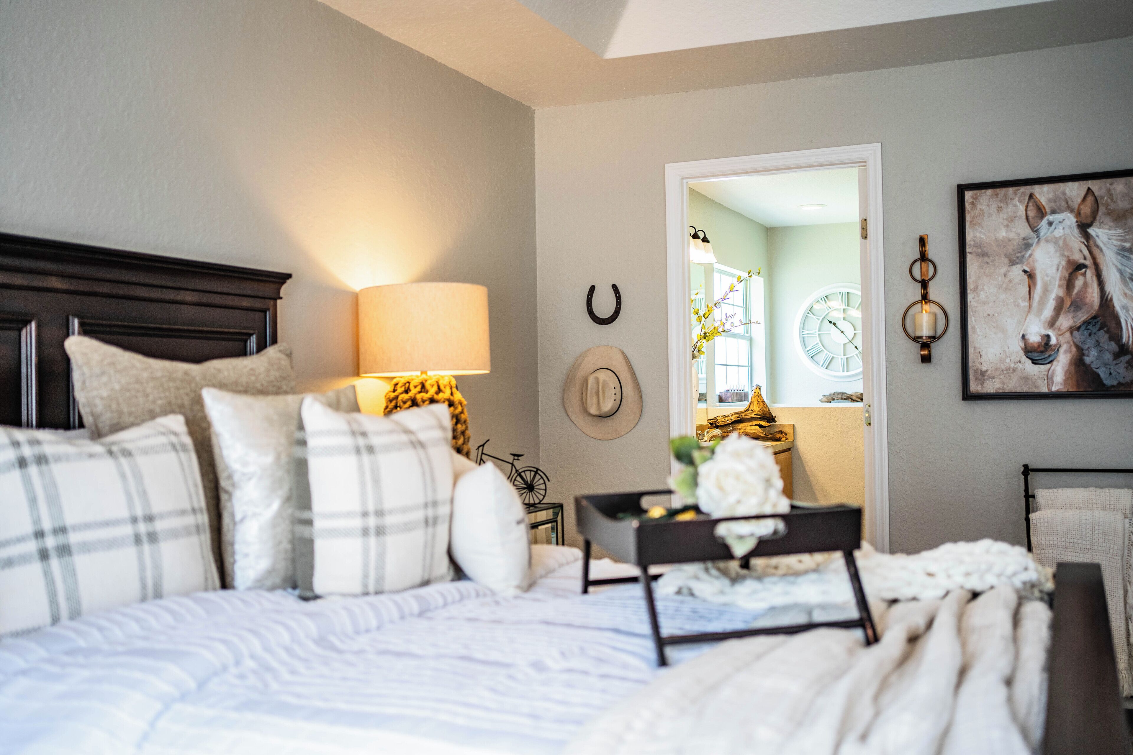 A bedroom with a bed, bedside table, lamp, and a wall clock.