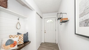 A hallway with a wooden bench, a white door, and a framed picture on the wall. - StayBurgundy Fairfield, OH (Fairfield)