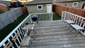 A deck with wooden railings, a grill, and two chairs. - Brand new 2 bedroom basement in Leduc(10mins from YEG airport) (Leduc)