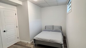 A bedroom with a bed, a door, and a ceiling with recessed lighting. - Brand new 2 bedroom basement in Leduc(10mins from YEG airport) (Leduc)