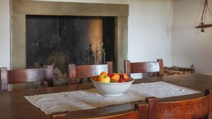 Une table à manger avec un saladier blanc rempli de fruits au centre, entourée de chaises en bois.