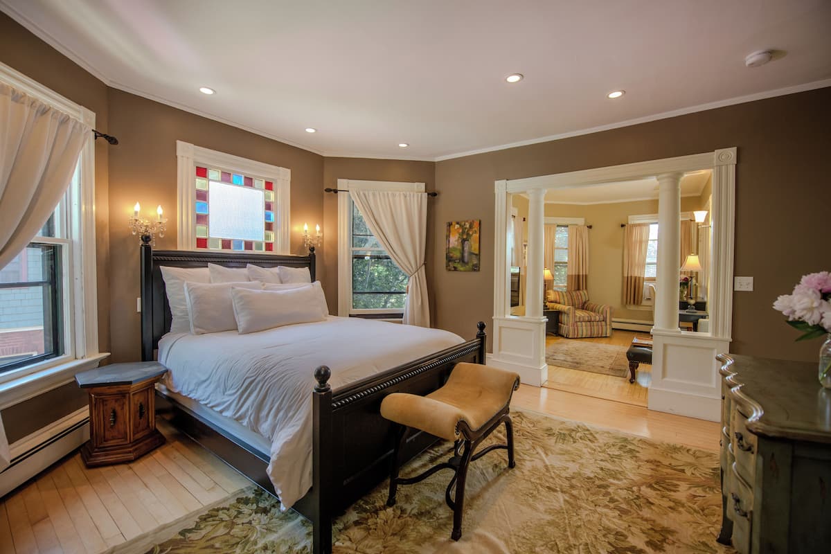 Een slaapkamer met een groot bed, een nachtkastje, een bankje en een dressoir.