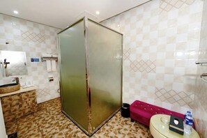 Et badeværelse med bruser, toilet, håndvask og spejl.