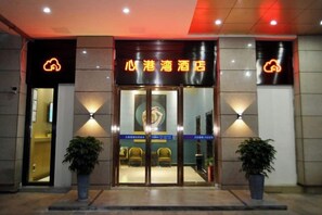 A hotel entrance with a glass door, a sign above the door, and two potted plants on either side. - Changsha Xingangwan Hotel (Changsha)