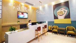 A reception area with a counter, bar stools, a TV, and a large poster on the wall. - Changsha Xingangwan Hotel (Changsha)
