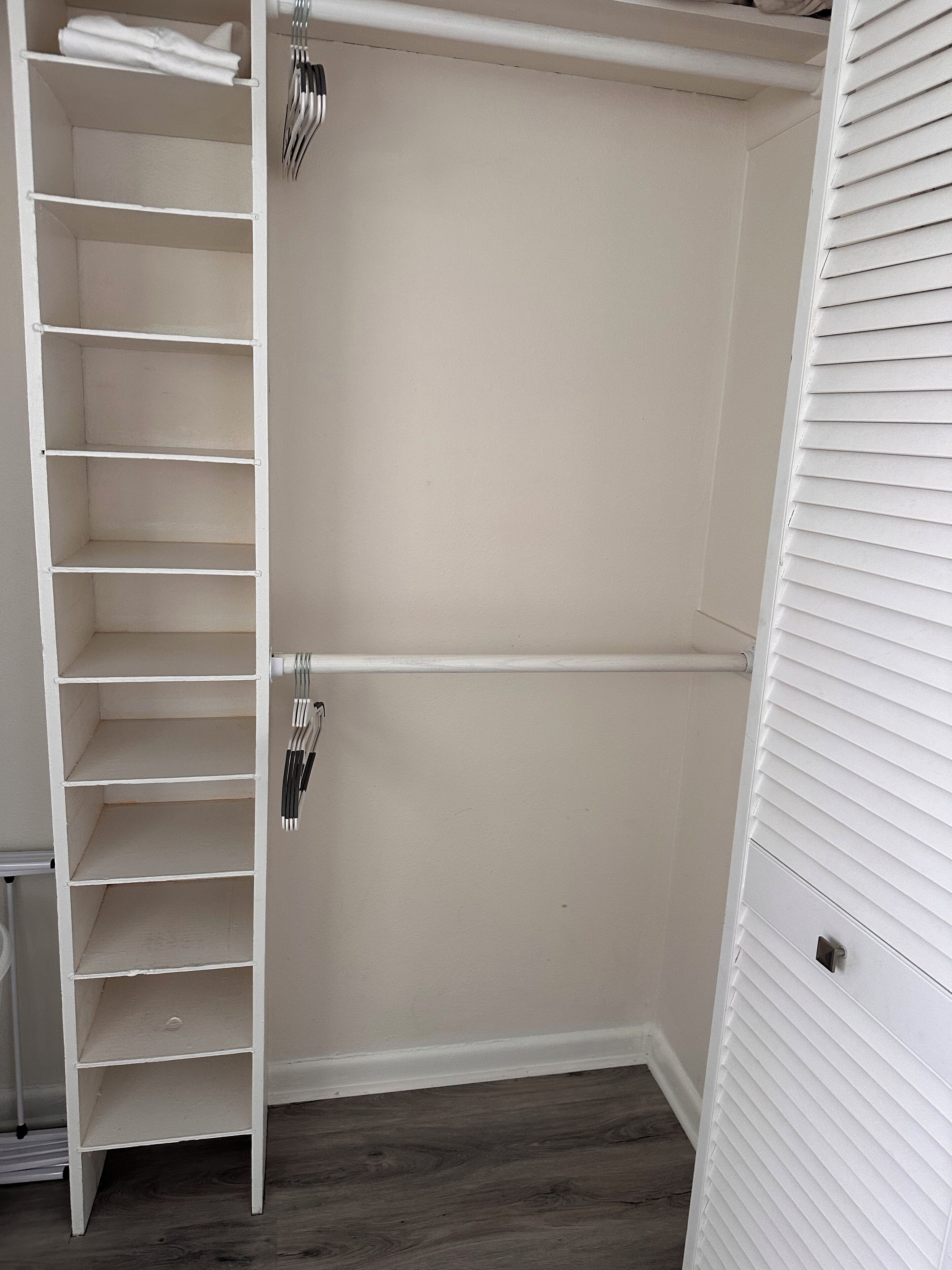 Um closet espaçoso com várias prateleiras e espaço para pendurar roupas.