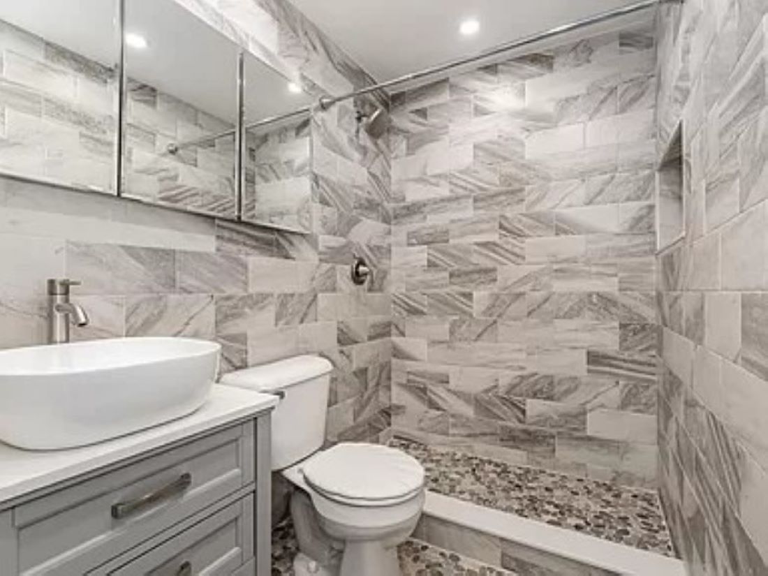 A bathroom with a marble sink, toilet, and shower area.