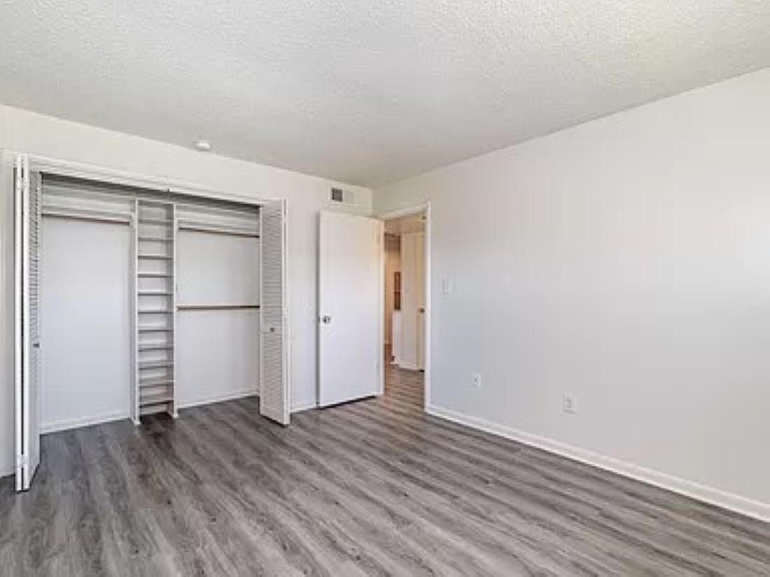 Una habitación con piso de madera, paredes blancas y un armario con escalera.
