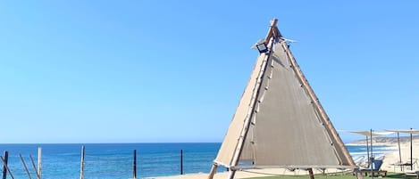 A clear blue sky, a beach, and a pool with a sailboat.