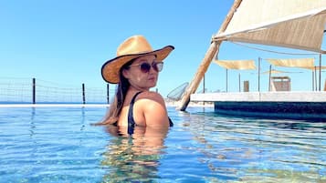A person in a swimming pool with a sailboat in the background.