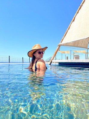 Eine Person im Schwimmbecken, im Hintergrund ein Segelboot.