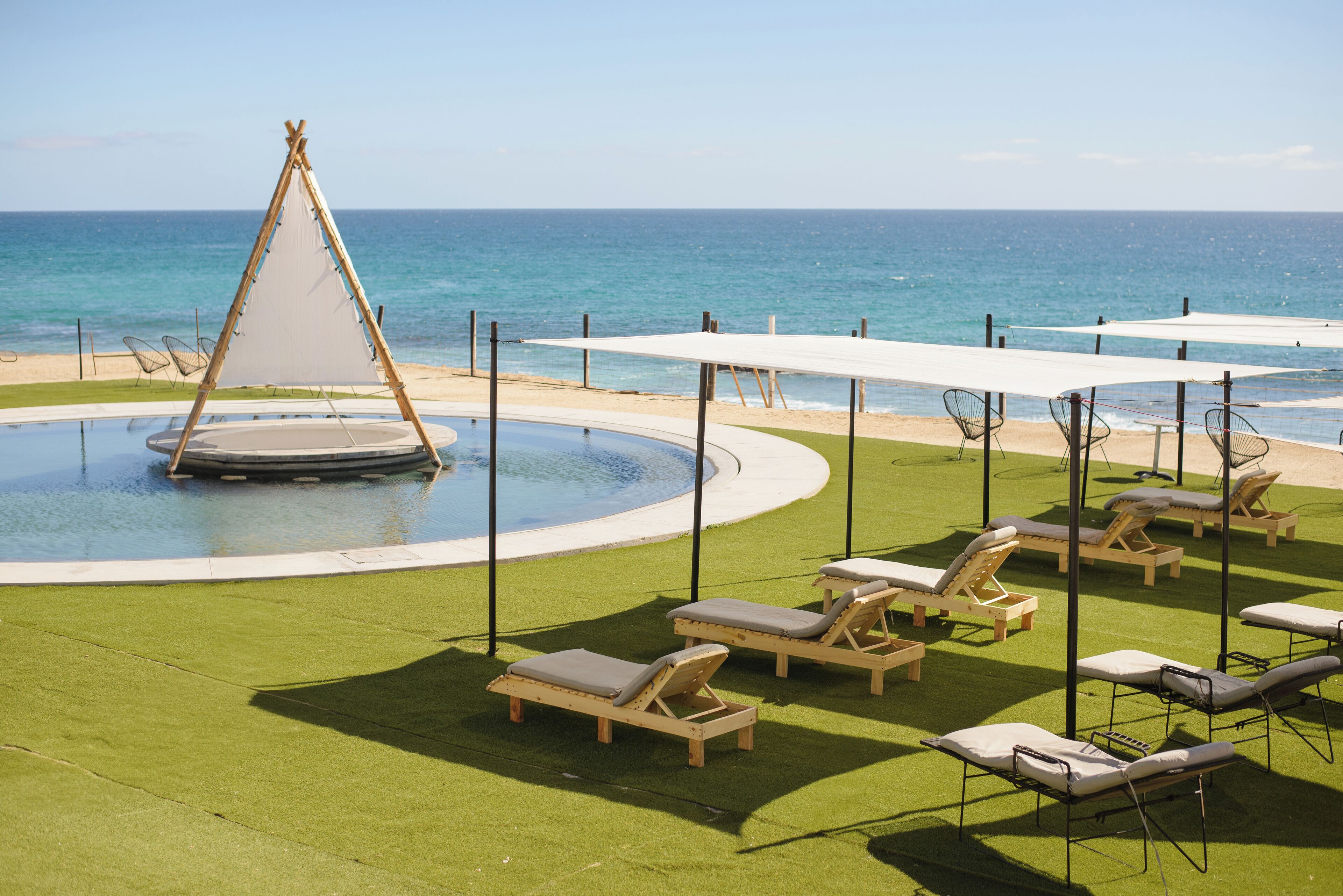 Un área de piscina con sillas de descanso y una estructura tipo carpa.