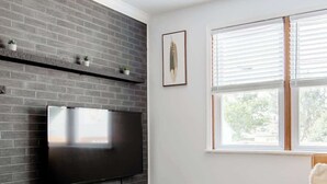 Un saló modern amb una llar de pedra, un televisor de pantalla plana, un sofà de cuir marró i dues taules rodones blanques.