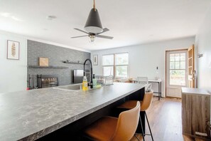 Una cocina moderna con una isla grande, un ventilador de techo y vistas al exterior.