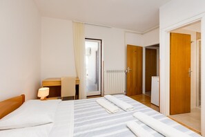 Ein Hotelzimmer mit Bett, Schreibtisch, Stuhl, Lampe und einem durchgegangenen Tür sichtbaren Badezimmer.