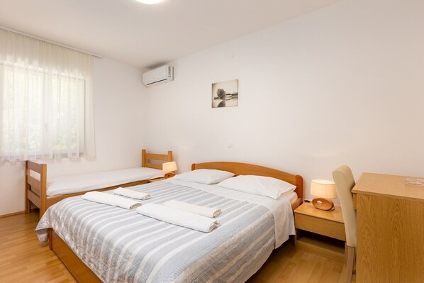 Ein Zimmer mit zwei Einzelbetten, einem Schreibtisch, einem Stuhl, einer Lampe und einem Bild an der Wand.