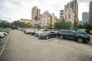 A parking lot with multiple cars and a bus, surrounded by residential buildings. - Crystal Orange (Shanghai Oriental Pearl Binjiang) (Shanghai)